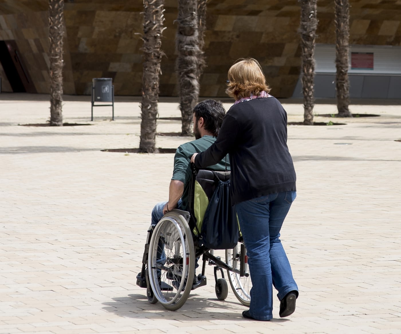 Cuidadora empeny cadira de rodes d'una persona discapacitada