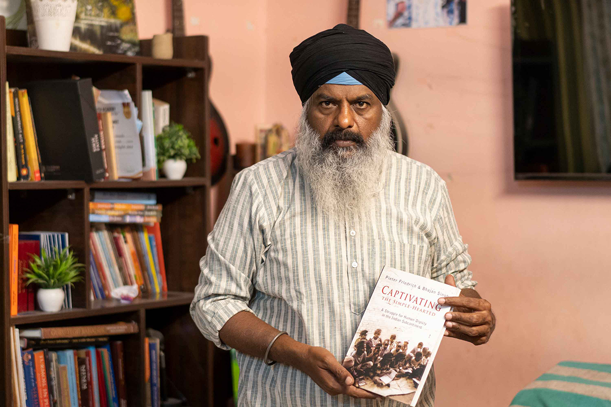Jeevan Singh, a casa seva a Nova Delhi, posa amb un llibre que el va inspirar