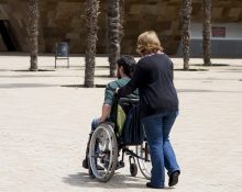 Cuidadora empeny cadira de rodes d'una persona discapacitada