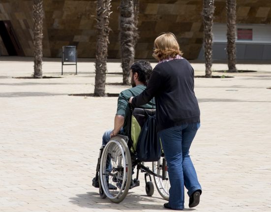 Cuidadora empeny cadira de rodes d'una persona discapacitada