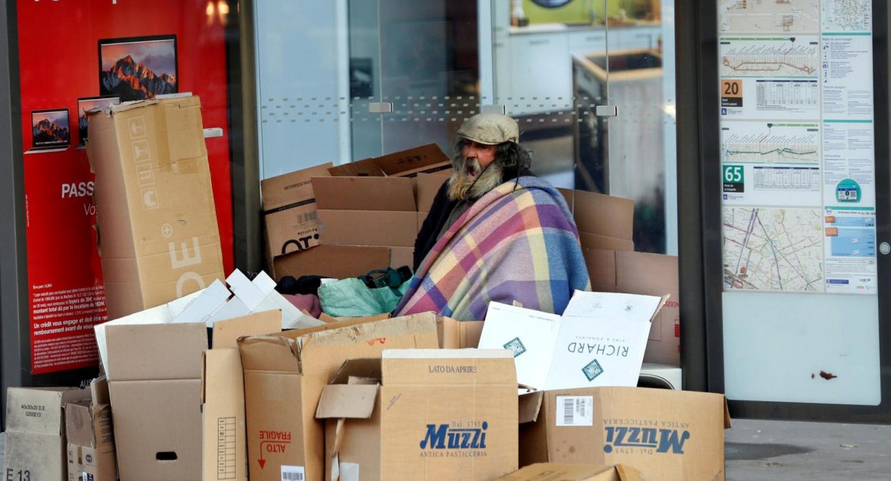 Un home en situació de carrer resguardat rere els cartrons a París | © Charles Platiau - Reuters