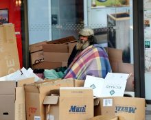 Un home en situació de carrer resguardat rere els cartrons a París | © Charles Platiau - Reuters