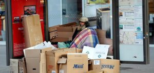 Un home en situació de carrer resguardat rere els cartrons a París | © Charles Platiau - Reuters