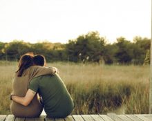 Una parella d'enamorats s'abraça davant un bosc poblat de vegetació - Freepik