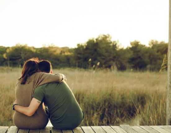 Una parella d'enamorats s'abraça davant un bosc poblat de vegetació | © Freepik