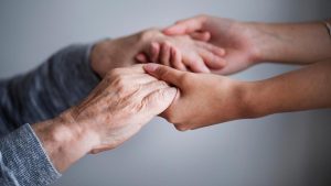 Mans entrellaçades de persona cuidadora i persona cuidada