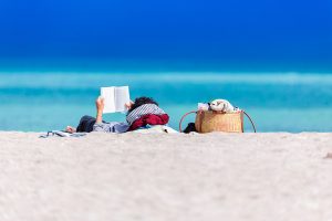 Una persona llegint a la platja