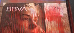 Un cartell del BBVA tacat de pintura vermella en una acció coordinada pel grup antimilitarista de Bilbao KEM-MOC